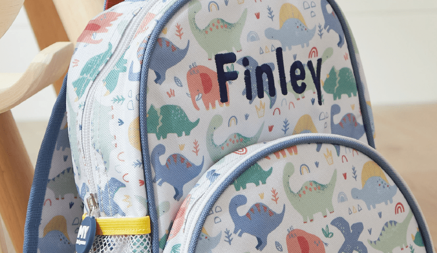 multicoloured backpack with dinosaurs and name Finley on the front